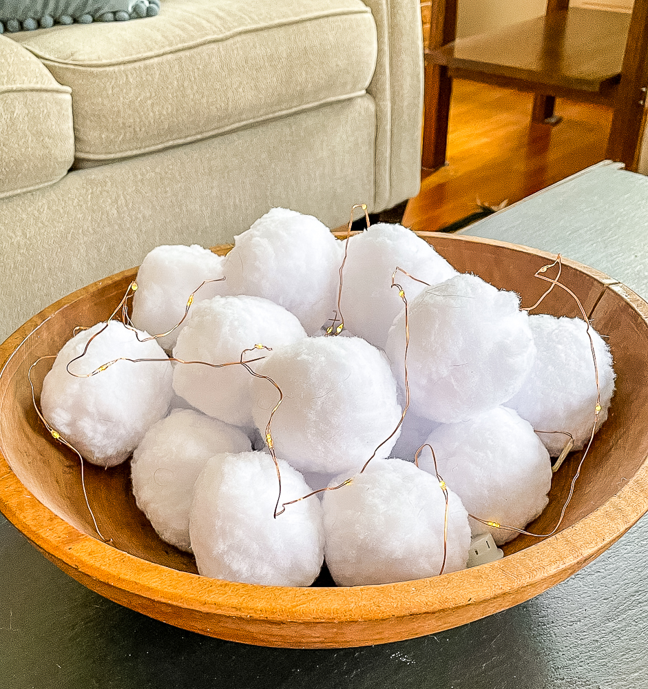 Faux snowballs with twinkle lights in a wooden bowl